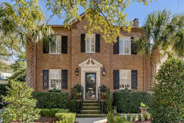 view of front facade featuring brick siding and a chimney