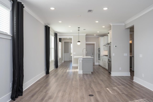 kitchen featuring light countertops, a sink, ornamental molding, and light wood finished floors