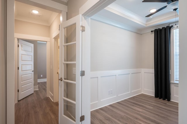 hall with a decorative wall, ornamental molding, dark wood-type flooring, and wainscoting