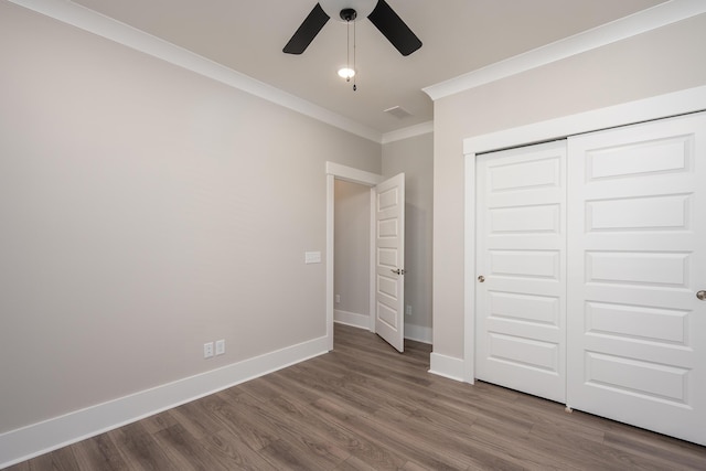 unfurnished bedroom with a closet, crown molding, baseboards, and wood finished floors