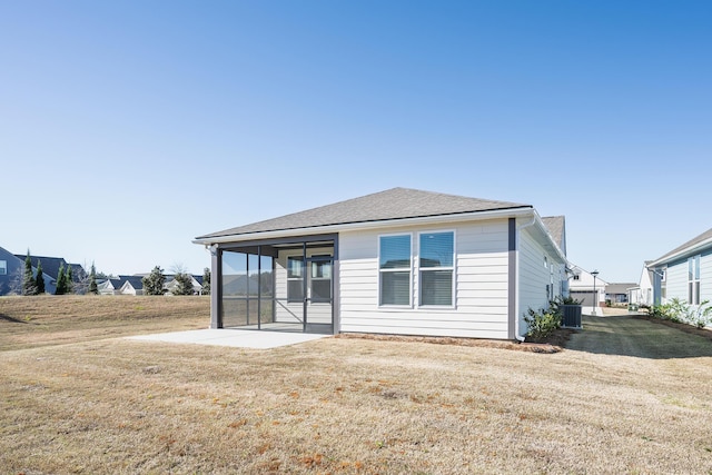 rear view of house featuring a sunroom, a shingled roof, cooling unit, and a yard