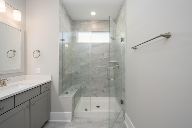 full bath featuring vanity, baseboards, and a shower stall