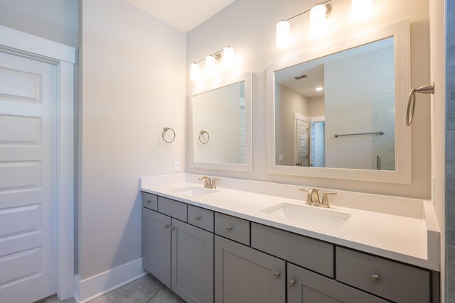 bathroom with baseboards, double vanity, visible vents, and a sink