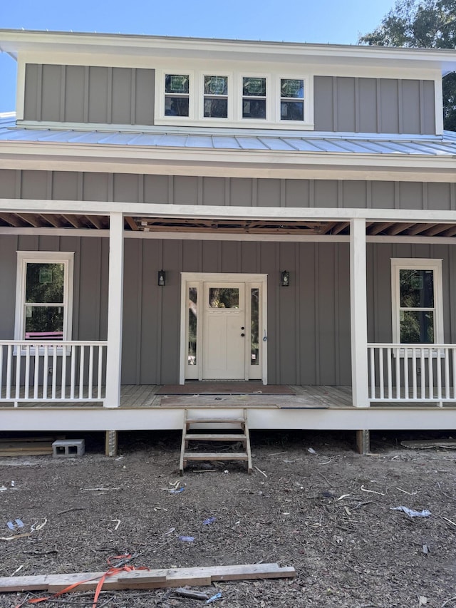 view of exterior entry with a porch and board and batten siding