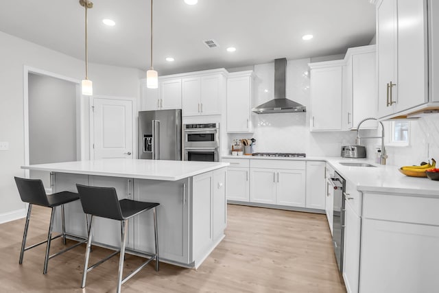 kitchen with stainless steel appliances, a kitchen island, wall chimney exhaust hood, and sink