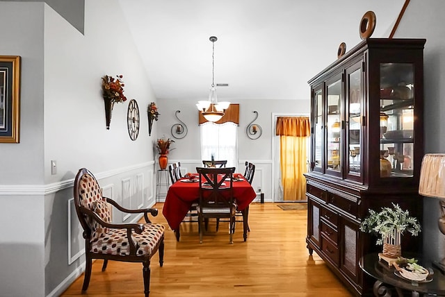 8692 Bentwood Dr, North Charleston, SC 29406 - dining space featuring a chandelier, light wood-style flooring, a wainscoted wall, and lofted ceiling