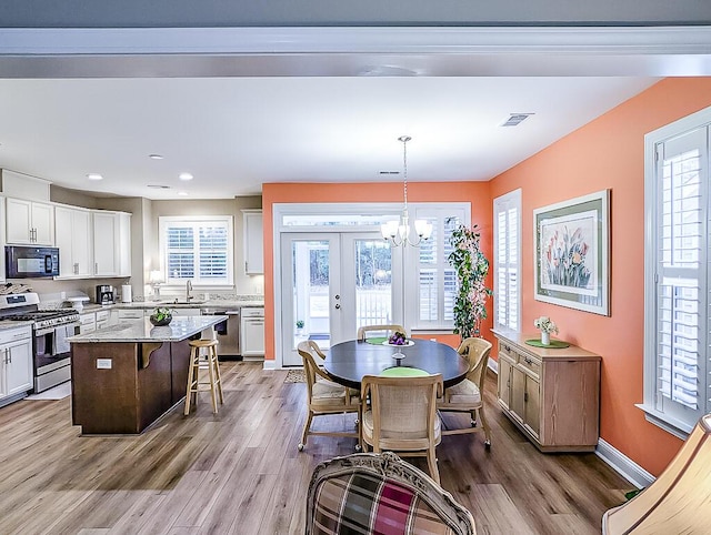 interior space with sink, french doors, a chandelier, and light wood-type flooring