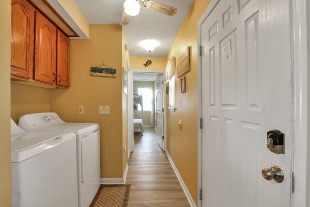 laundry room featuring cabinets, independent washer and dryer, a textured ceiling, and light hardwood / wood-style flooring