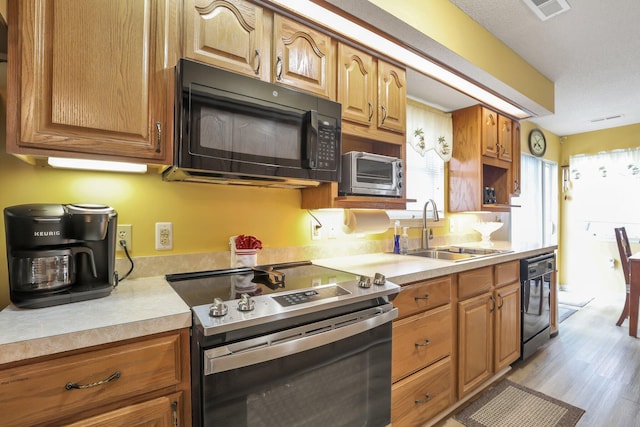 kitchen featuring black appliances, sink, and light hardwood / wood-style flooring