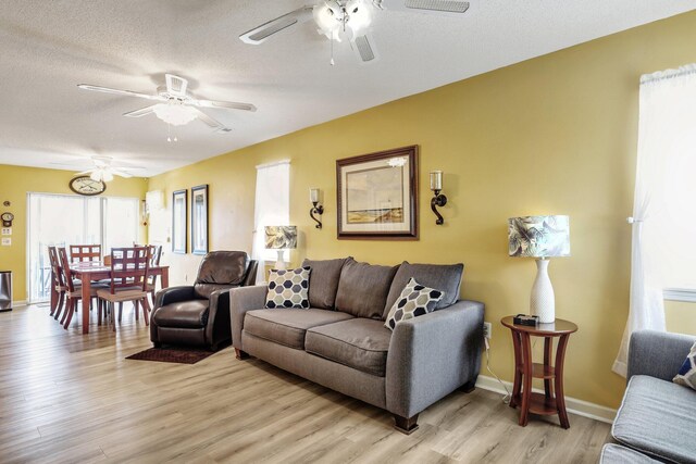 living room with a textured ceiling, light hardwood / wood-style flooring, and ceiling fan