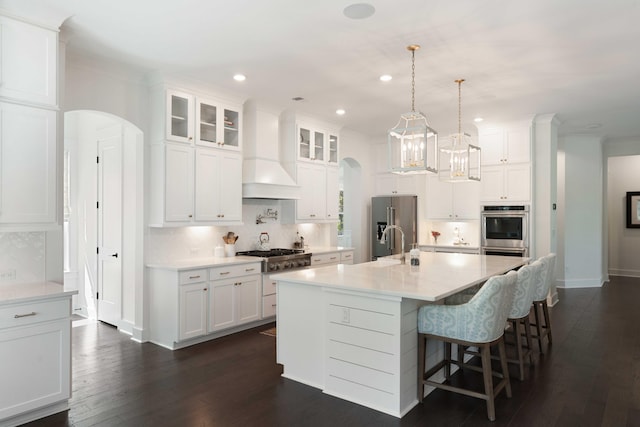 kitchen with arched walkways, tasteful backsplash, and custom exhaust hood