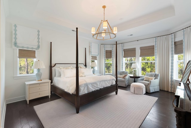 bedroom with dark wood-style floors, a tray ceiling, an inviting chandelier, and multiple windows
