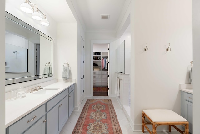 bathroom featuring crown molding, a tile shower, a walk in closet, vanity, and visible vents