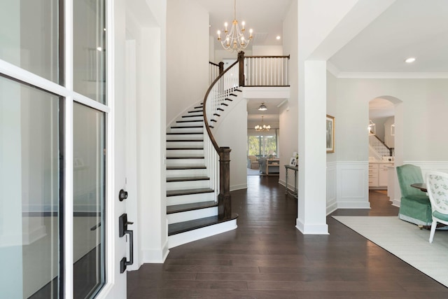 entryway featuring stairs, arched walkways, a notable chandelier, and dark wood-style floors