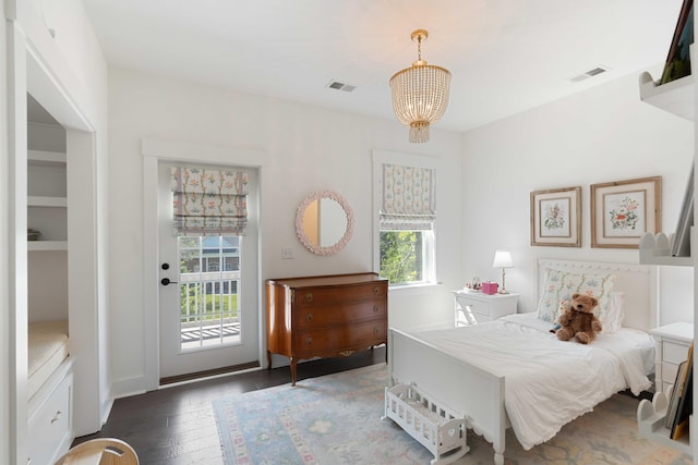 bedroom featuring visible vents, access to exterior, wood finished floors, and an inviting chandelier