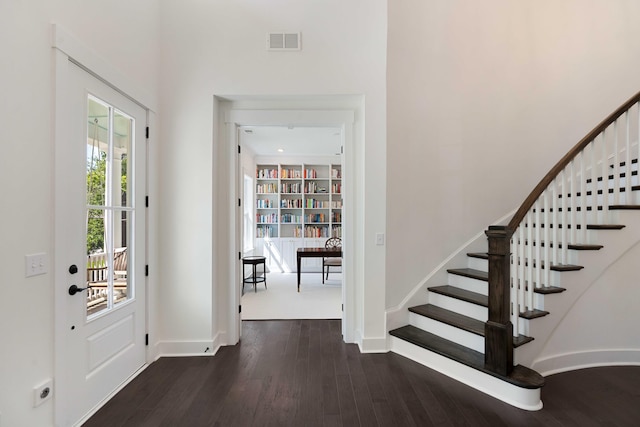 foyer featuring visible vents, wood finished floors, and stairway