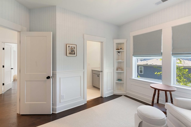 sitting room featuring a decorative wall, wallpapered walls, a wainscoted wall, and dark wood-type flooring