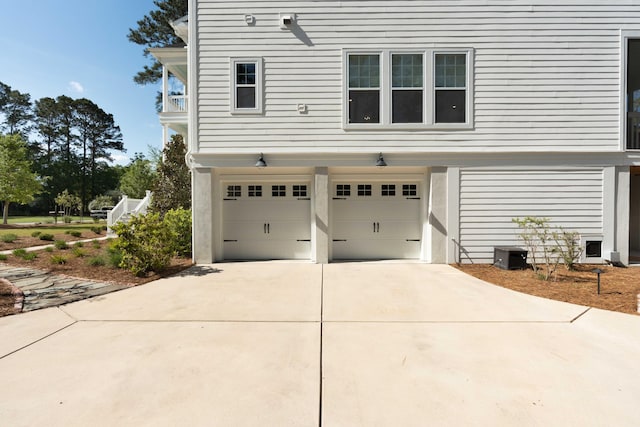 view of side of home featuring an attached garage, a balcony, and concrete driveway