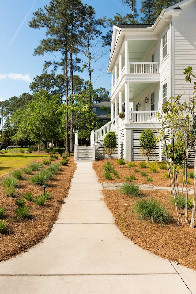 view of property exterior with a porch, stairway, and a balcony