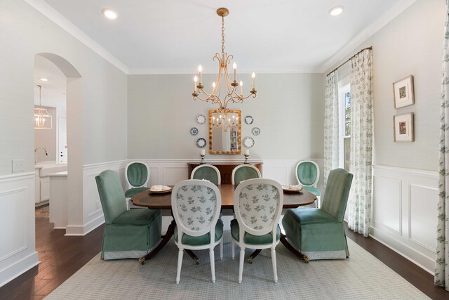 dining space featuring crown molding, dark wood-style flooring, an inviting chandelier, a decorative wall, and arched walkways
