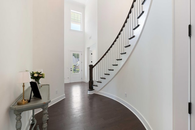 foyer featuring stairway, baseboards, a towering ceiling, and dark wood-type flooring