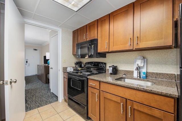 kitchen with light tile patterned floors, dark stone countertops, sink, and black appliances