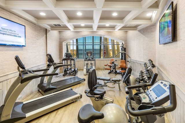 workout area with coffered ceiling and hardwood / wood-style floors