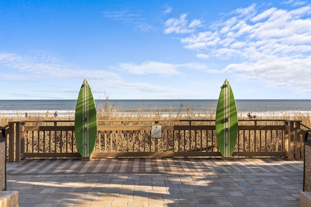 view of patio with a water view and a view of the beach