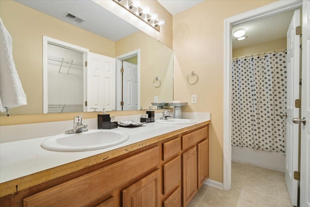 bathroom featuring vanity, tile patterned flooring, and a textured ceiling