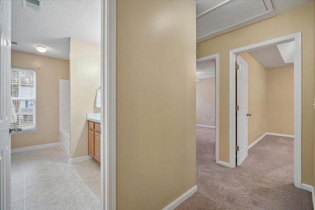 corridor with light tile patterned floors and a textured ceiling