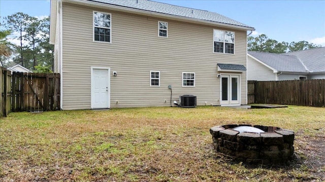 rear view of house with a yard, cooling unit, and a fire pit