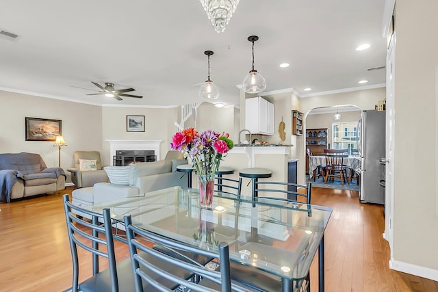 544 Beverly Dr, Summerville, SC 29485 - dining room featuring ornamental molding, a ceiling fan, visible vents, arched walkways, and light wood finished floors