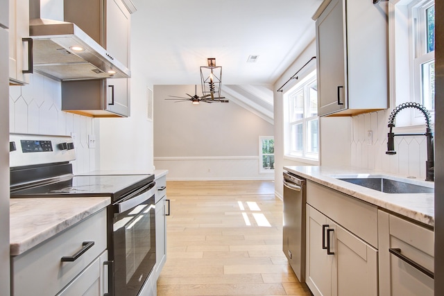 1052 Yorktown Dr, Charleston, SC 29412 - kitchen featuring stainless steel appliances, extractor fan, light wood-style floors, lofted ceiling, and light stone counters