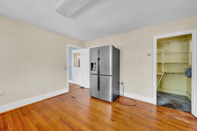 kitchen featuring stainless steel fridge with ice dispenser, baseboards, and wood finished floors