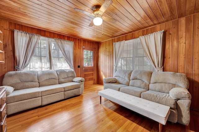 living area with wood ceiling, wood walls, wood finished floors, and a ceiling fan
