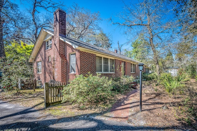 view of side of home featuring brick siding and a chimney