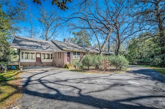 single story home featuring brick siding, driveway, a chimney, and entry steps
