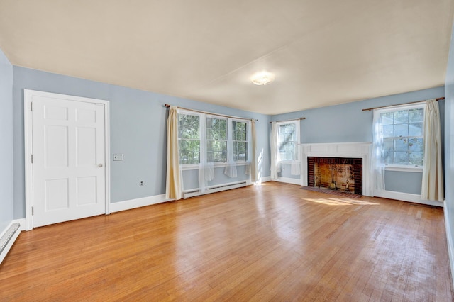 unfurnished living room with a baseboard heating unit, a brick fireplace, light wood-style flooring, and plenty of natural light