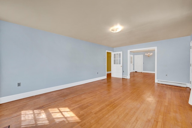 unfurnished room featuring a baseboard heating unit, baseboards, an inviting chandelier, and light wood-type flooring