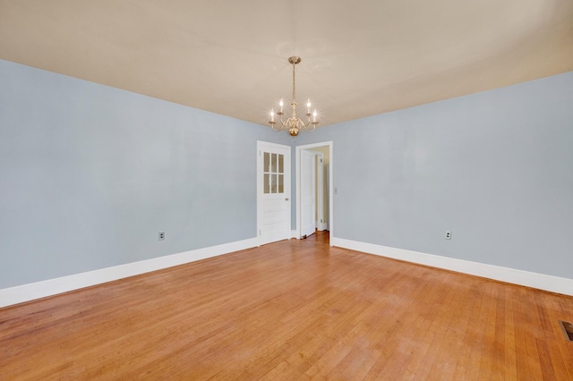 unfurnished room featuring light wood-style floors, a chandelier, and baseboards