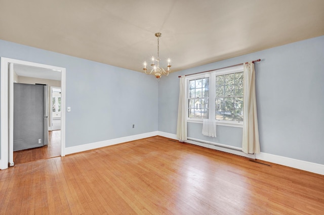 unfurnished room featuring an inviting chandelier, a baseboard radiator, baseboards, and wood finished floors