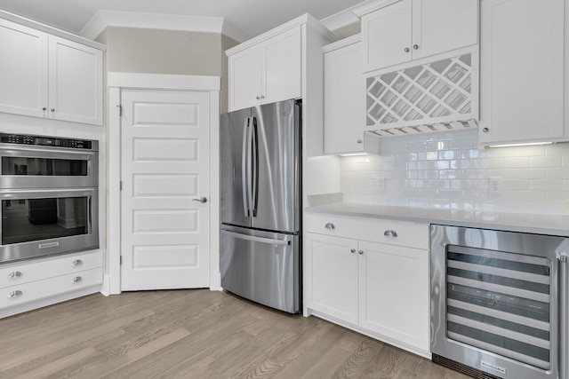 kitchen with white cabinetry, beverage cooler, decorative backsplash, light hardwood / wood-style floors, and stainless steel appliances