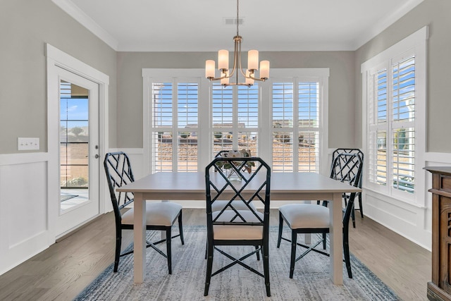 dining area with an inviting chandelier, ornamental molding, and wood-type flooring