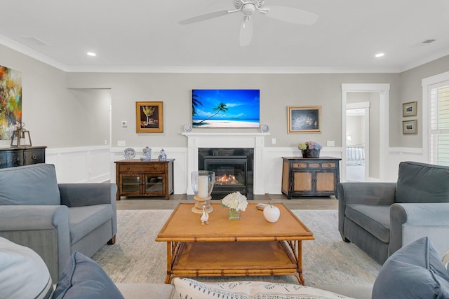 living room featuring crown molding, ceiling fan, and light wood-type flooring