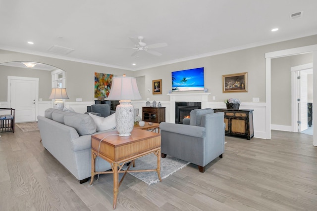 living room featuring ceiling fan, ornamental molding, and light wood-type flooring