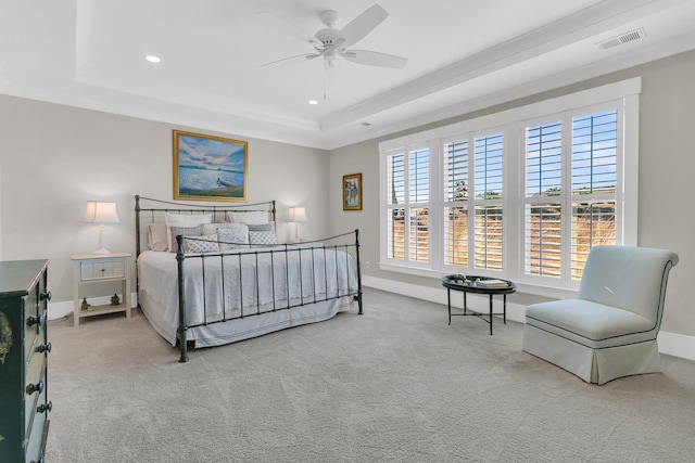 carpeted bedroom with a raised ceiling and ceiling fan