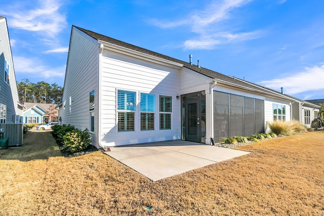 rear view of property with a lawn, a sunroom, central AC, and a patio area