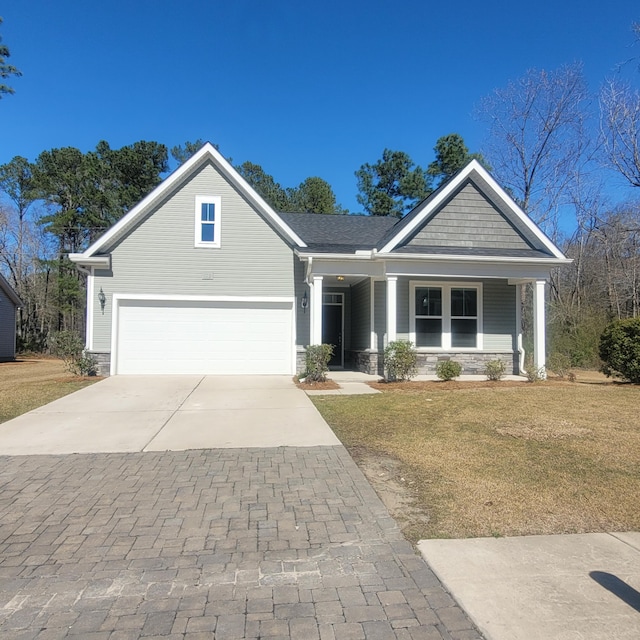 view of front facade featuring driveway, stone siding, a garage, and a front lawn