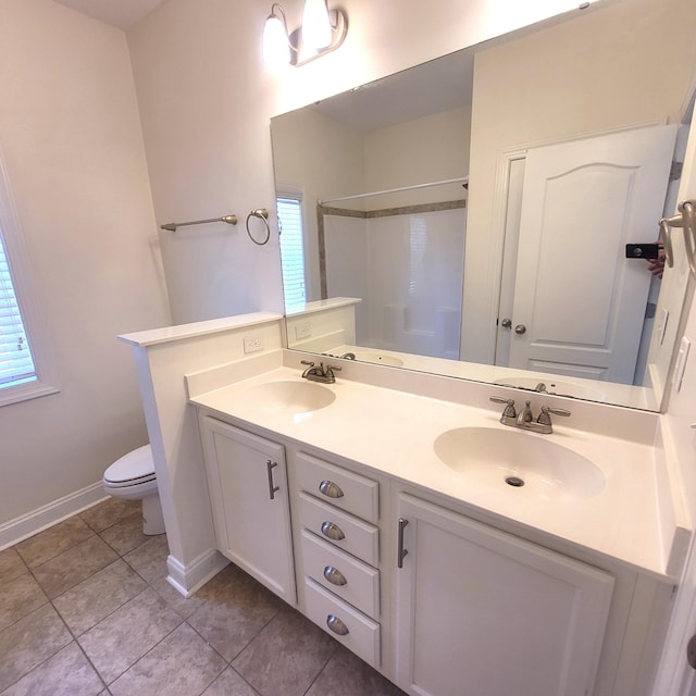 bathroom featuring double vanity, tile patterned flooring, a sink, and toilet