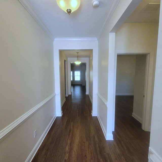 hall featuring visible vents, baseboards, dark wood finished floors, and crown molding